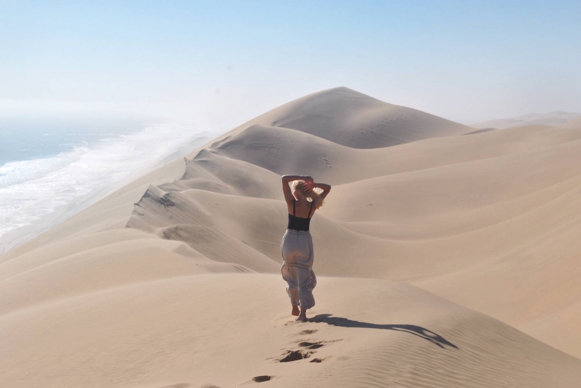 woman standing in front of an African sand dune